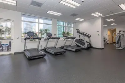 a gym with treadles and ellipticals in a room with windows at LuxBright 1BR Brickell Paradise with Oceanview and Parking in Miami