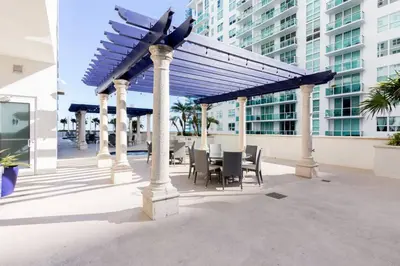 a patio with tables and chairs under a blue canopy at LuxBright 1BR Brickell Paradise with Oceanview and Parking in Miami