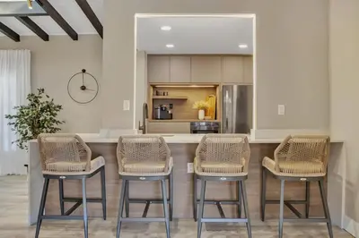 a kitchen with three bar stools and a counter at Stunning 2 Story Villa with Pool in Fort Lauderdale