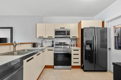 a kitchen with a stainless steel refrigerator and white cabinets at Waterfront Luxury 2-Bedroom Condo Sunny Isles Beach in Miami Beach