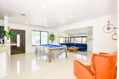 a living room with a ping pong table and an orange chair at Five Bedroom Villa With POOL In Highland Lakes Near Aventura Mall in Miami