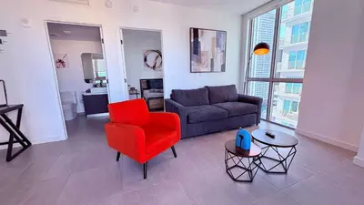a living room with a couch and a red chair at Sky-High oasis heated Pool & Gym Miami Skyline Vista in Miami