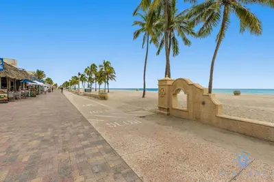 a sidewalk next to a beach with palm trees at Spectacular Beach View - Amazing Rooftop Pool in Hollywood