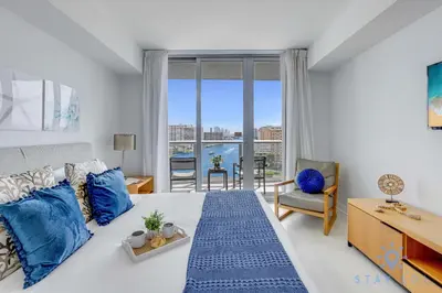 a bedroom with a large bed with blue pillows at Infinite View Balcony with Pool, Gym and Near Beach in Hallandale Beach
