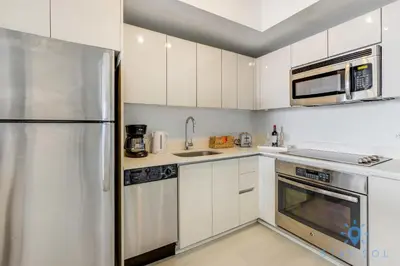 a kitchen with white cabinets and a stainless steel refrigerator at Infinite View Balcony with Pool, Gym and Near Beach in Hallandale Beach