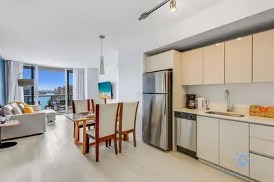 a kitchen and living room with a table and chairs at Infinite View Balcony with Gym, Pool and Near Beach in Hallandale Beach