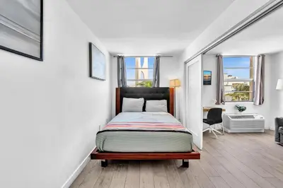 a bedroom with a bed in a room with windows at Deluxe modern 1 bedroom in south beach in Miami Beach