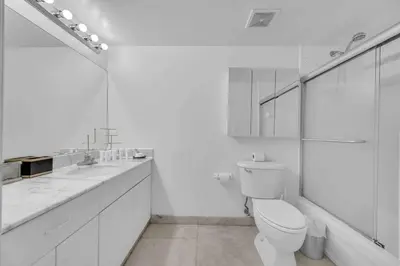 a white bathroom with a toilet and two sinks at Iconic High floor 3 bedrooms in the heart of Miami in Miami