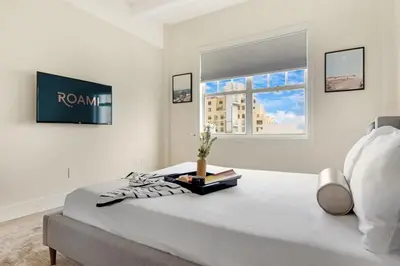 a white bedroom with a bed and a window at Roami at The Alamac in Miami Beach