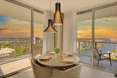a dining room with a table and chairs and large windows at High Floor with Stunning Views Amazing Pools in Hollywood