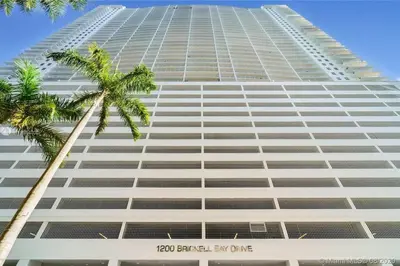 a tall building with a palm tree in front of it at Amazing cozy Condo in Brickell Miami in Miami