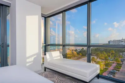 a bedroom with a white bed and large windows at Oceanfront Private Residence at South Beach - 828 in Miami Beach