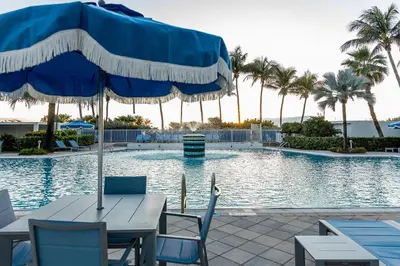 a table with an umbrella next to a swimming pool at Sherry Frontenac Oceanfront in Miami Beach
