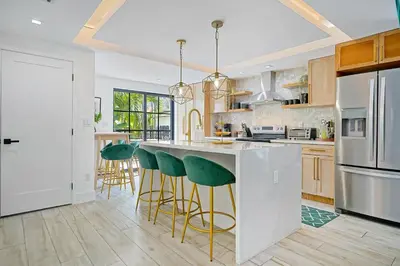 a kitchen with a large island with green bar stools at Villa Verde Miami in Miami