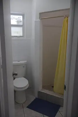 a bathroom with a toilet and a yellow shower curtain at Rainbow Motel Miami in Miami