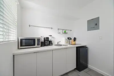 a white kitchen with a microwave and a sink at Wonderful Studio Residence 15 min from the beach in Miami
