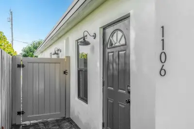 a door on a white house with a fence at Lauderdale Modern 1 Bedroom 1 Bathroom with Private Backyard in Fort Lauderdale