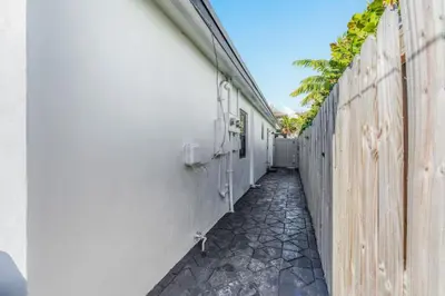 a walkway next to a white building with a fence at Lauderdale Modern 1 Bedroom 1 Bathroom with Private Backyard in Fort Lauderdale