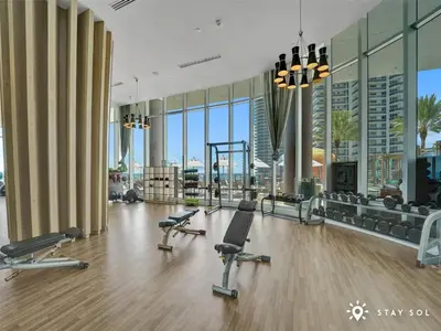 a gym with exercise equipment in a building with windows at Ocean View Balcony Beachfront Resort Amazing Pools in Hollywood