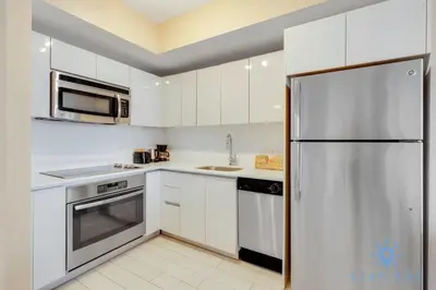 a kitchen with white cabinets and a stainless steel refrigerator at Pool - Apartment with Balcony - Gym - Near Beach in Hallandale Beach