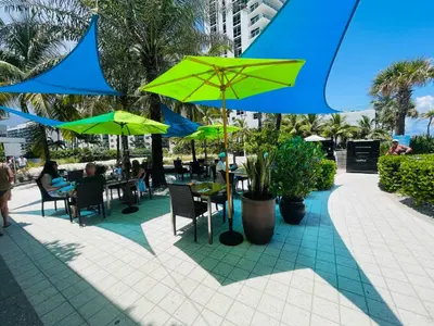 a group of people sitting at tables with green umbrellas at Beautiful penthouse condo with stunning views of both ocean and city in Hollywood