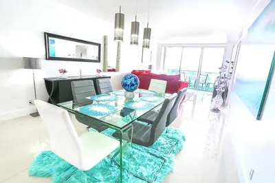 a dining room with a glass table and white chairs at Beautiful penthouse condo with stunning views of both ocean and city in Hollywood