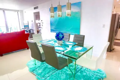 a dining room with a glass table and chairs at Beautiful penthouse condo with stunning views of both ocean and city in Hollywood