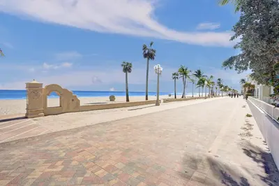 a walkway next to the beach with palm trees at Hollywood Apartments Host by BeeNomad in Hollywood
