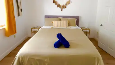 a bed with a pair of blue shoes sitting on it at Intimate Casita Mia minutes away from Airport, Calle 8, Brickell, Coral Gables, The beach and more! in Miami