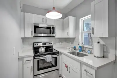 a white kitchen with a stove and a sink at Unique Las Olas Stay Pool Free Parking in Fort Lauderdale