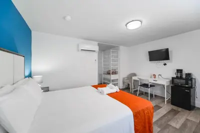 a bedroom with a white bed with an orange blanket at Beachfront Studio with Pool access -M24 in Hollywood