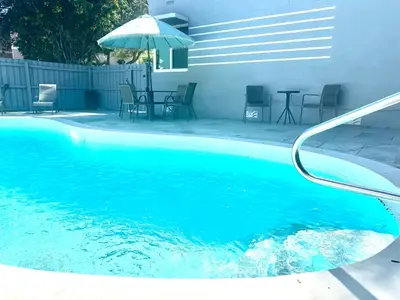 a blue swimming pool with a table and an umbrella at Walk to Las Olas Pool Perfect Couples Stay in Fort Lauderdale