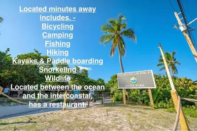 a sign in front of a beach with a palm tree at Walk to Las Olas Pool Perfect Couples Stay in Fort Lauderdale