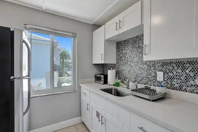 a kitchen with white cabinets and a sink and a window at Walk to Las Olas Pool Perfect Couples Stay in Fort Lauderdale