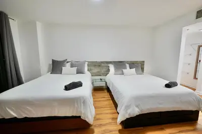 two beds in a room with white walls and wood floors at City & Sea View+FREE Parking Modern Condo in Miami