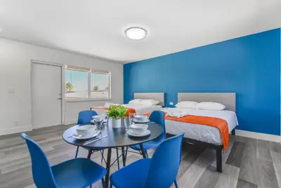 a room with a bed and a table with blue chairs at Magical Beach Escape with Pool -M37 in Hollywood