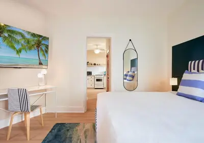 a white bedroom with a bed and a desk and a mirror at Pantera Rosa in Miami Beach