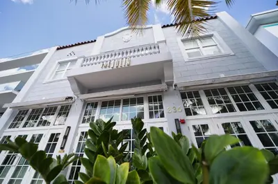 a white building with windows and a palm tree at The Julia Hotel in Miami Beach