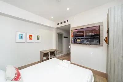 a bedroom with a bed and a tv on a wall at The Julia Hotel in Miami Beach