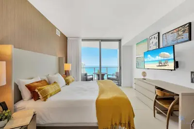 a bedroom with a large bed with a desk and a view at Insane Ocean View Balcony, Beachfront Resort, Pool in Hollywood