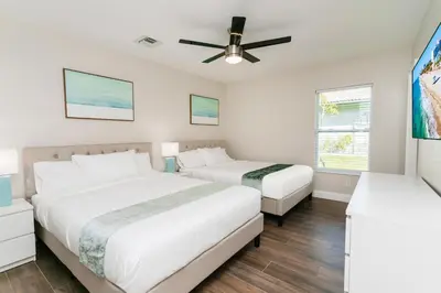 two beds in a bedroom with a ceiling fan at Luxury 5BR Villa Heated Pool near Beach & Casino in Dania Beach