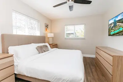 a bedroom with a white bed and a ceiling fan at Luxury 5BR Villa Heated Pool near Beach & Casino in Dania Beach