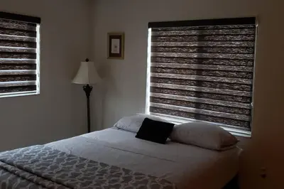 a bedroom with a bed and two large windows at Pool home in Miami in Tamiami