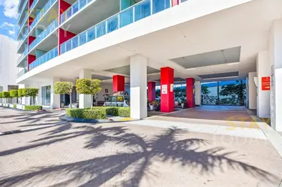 a shadow of a palm tree in front of a building at Beachwalk Resort - Waterfront huge 3-Bedroom apartment with direct ocean-view! in Hallandale Beach