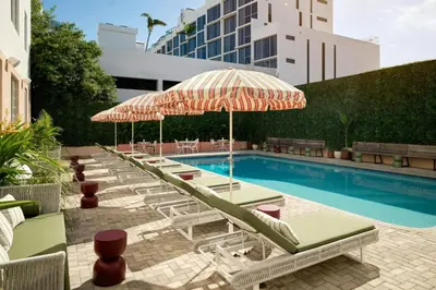 a row of lounge chairs and umbrellas next to a swimming pool at FOUND Hotels, Miami Beach, Series by Marriott in Miami Beach
