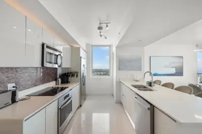 a kitchen with white cabinets and a sink and a microwave at BeachWalk Resort - VIP TOWER - OCEANVIEW UNIT 3 BEDROOM & 3 BATHROOM in Hallandale Beach