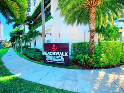 a sign in front of a building with palm trees at BeachWalk Resort - VIP TOWER - OCEANVIEW UNIT 3 BEDROOM & 3 BATHROOM in Hallandale Beach