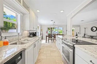 a large kitchen with white cabinets and a large island at Home wpool by PMI unit 332 in Fort Lauderdale