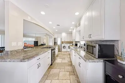 a kitchen with white cabinets and marble counter tops at Home wpool by PMI unit 332 in Fort Lauderdale