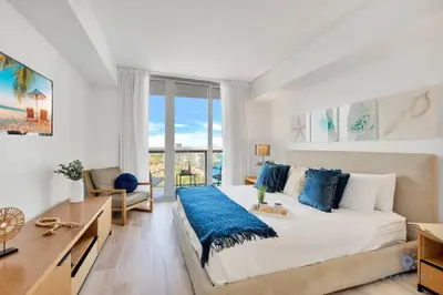a bedroom with a large bed with blue pillows at Amazing Pool - Gym - Complementary Shuttle in Hallandale Beach
